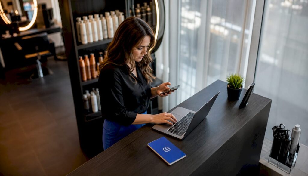 Salon manager working on CRM tablet and laptop