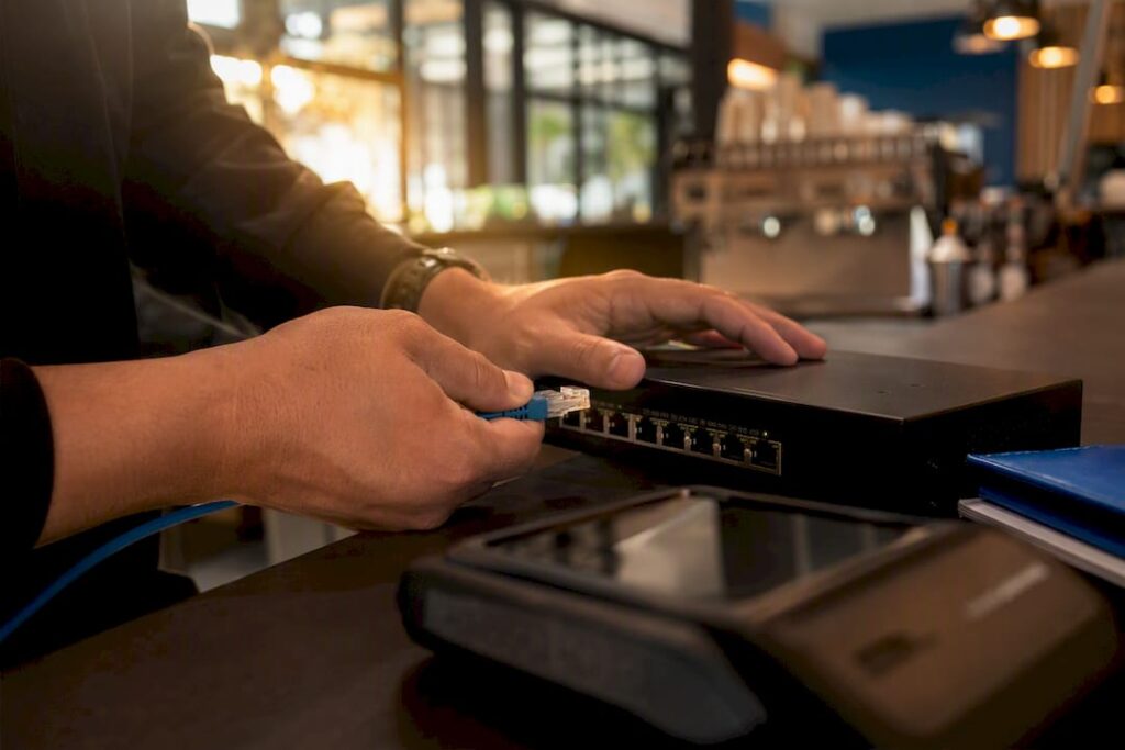 Hands plugging Ethernet cable into network switch